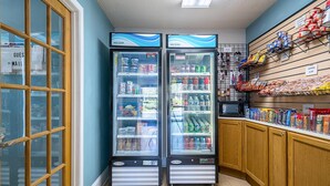 Een kleine buurtwinkel met twee gekoelde drankautomaten, diverse snacks en een afdeling voor gebak.