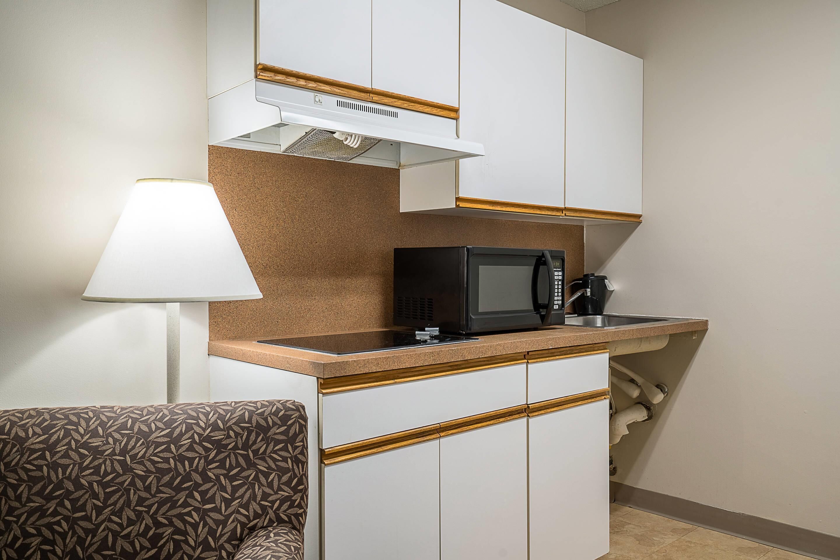 Una kitchenette compacta equipada con microondas, cafetera y un pequeño lavamanos.