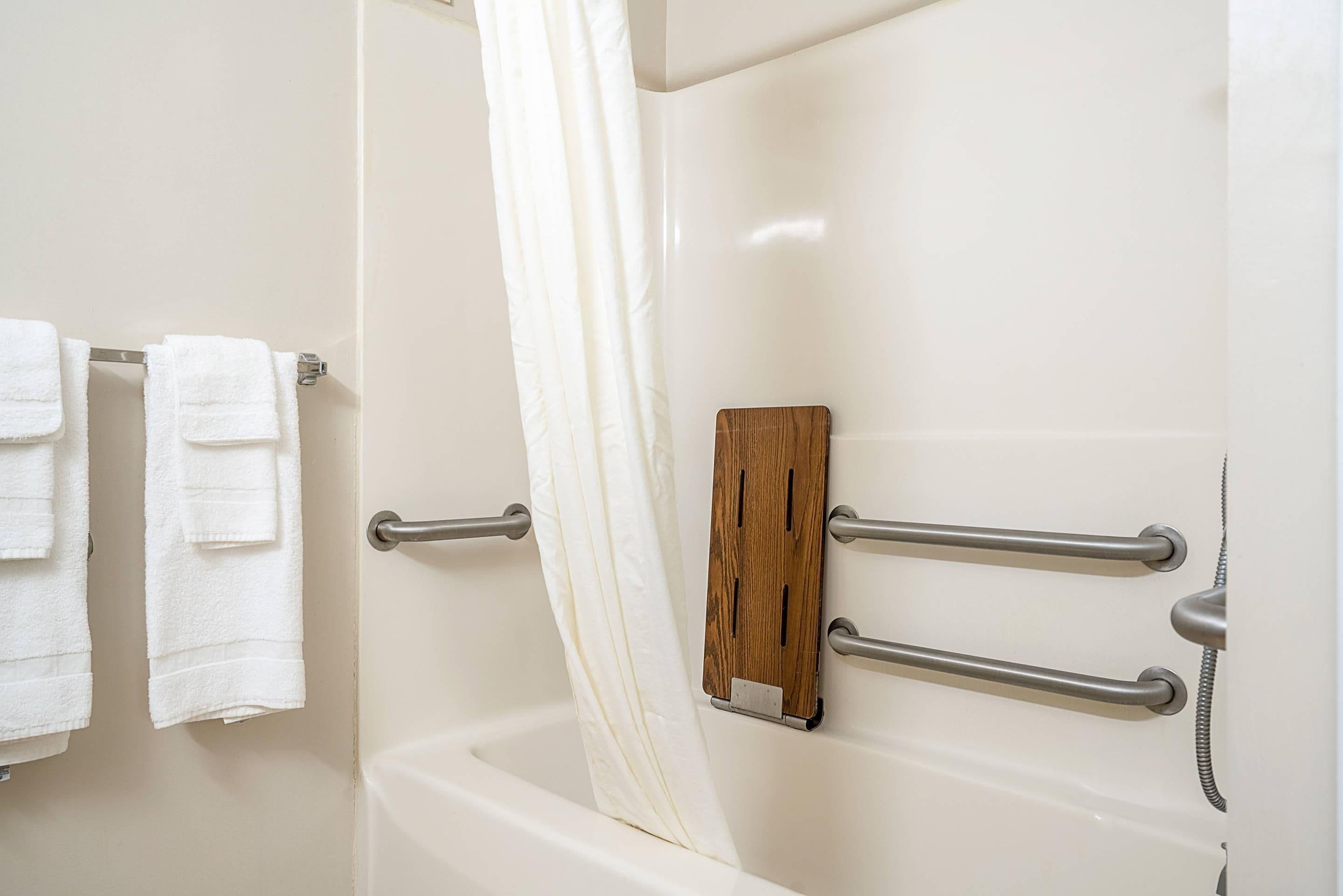 Un baño con una bañera, cortina de ducha y un perchero con dos toallas.
