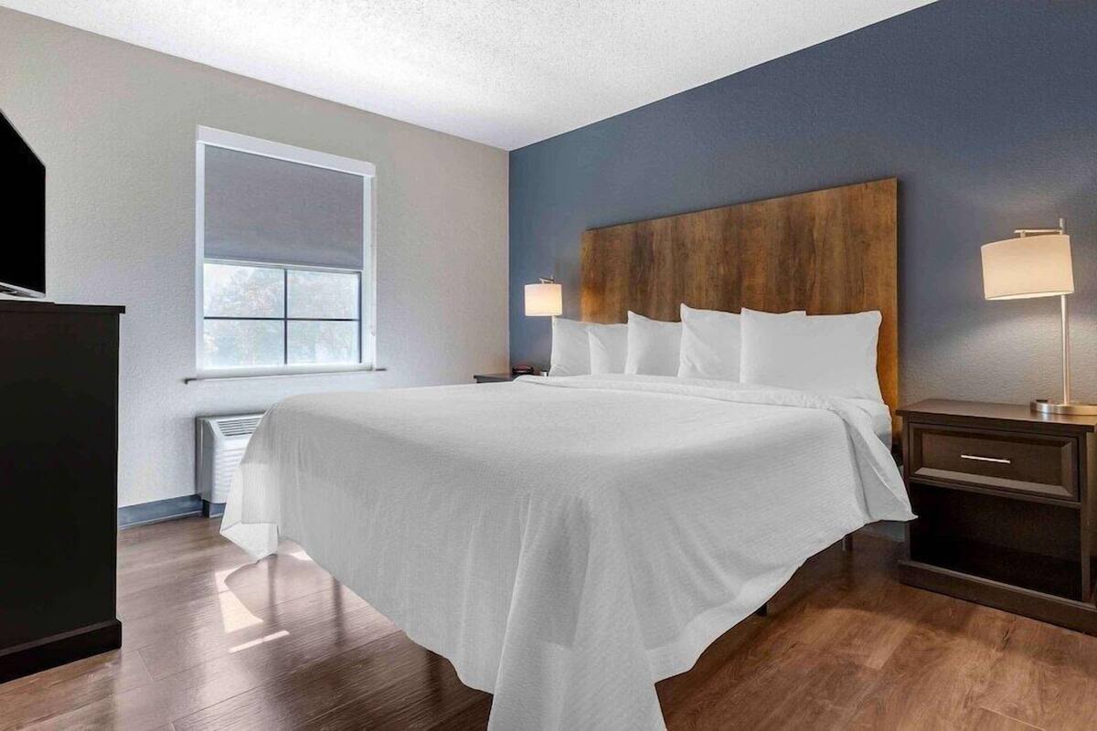 Habitación de hotel con una cama grande, una mesita de noche, una lámpara, una ventana y un radiador.