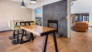 A modern living room with a fireplace, wooden flooring, and a dining area with a table and chairs. - Extended Stay America Premier Suites Charlotte Pineville Mat (Charlotte)