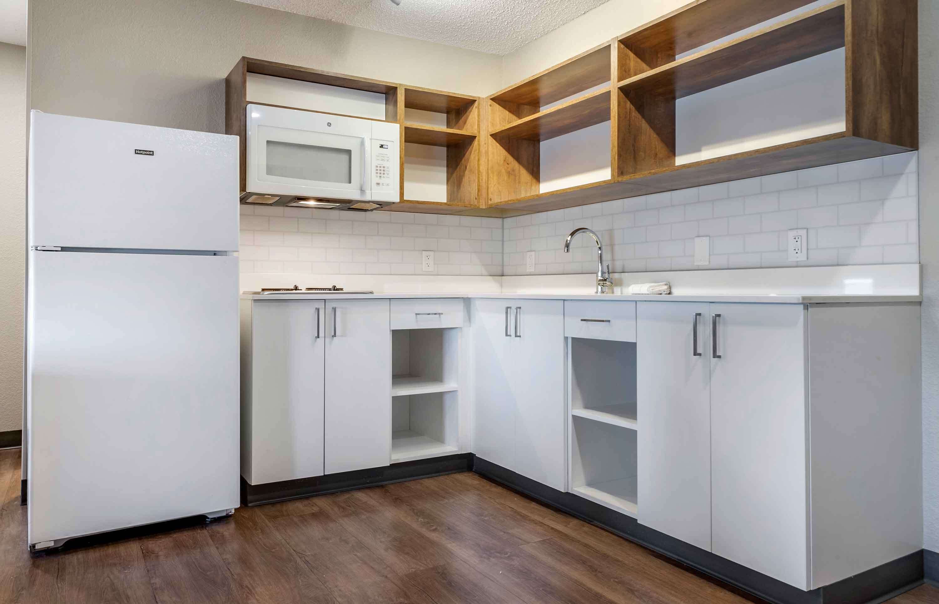 A modern kitchen with white cabinetry, a built-in microwave, and a stainless steel sink.