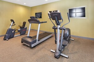 Gimnasio con cintas de correr, elípticas y una bicicleta estática.