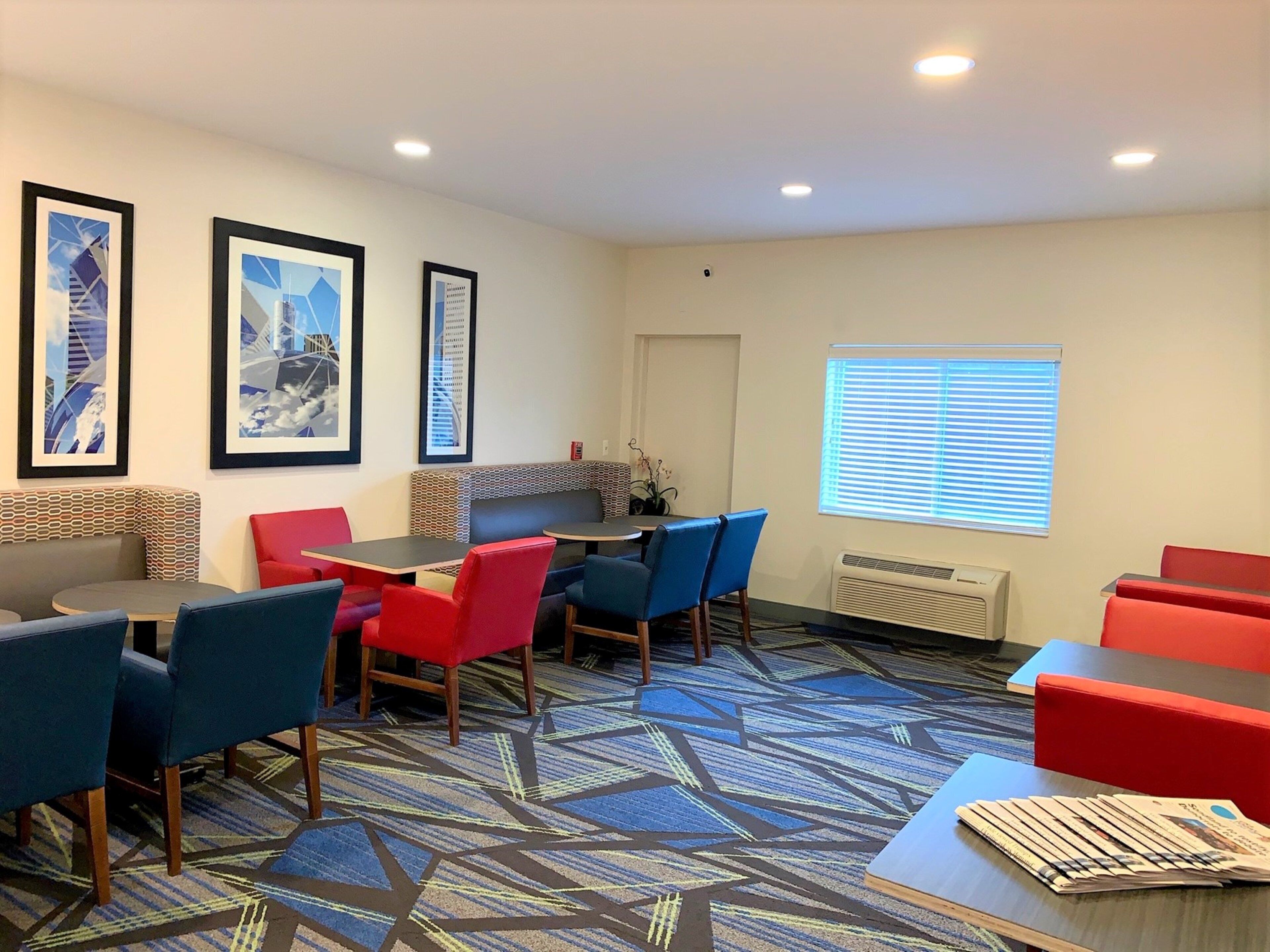 Habitación de hotel con comedor, alfombra estampada y cuadros en la pared.