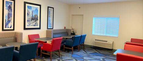 Habitación de hotel con comedor, alfombra estampada y cuadros en la pared.