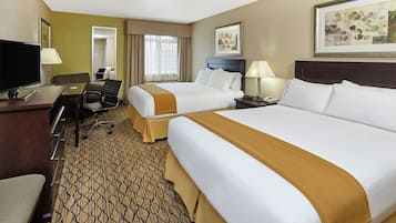 A hotel room with two beds, a desk with a TV, a chair, and a desk lamp.