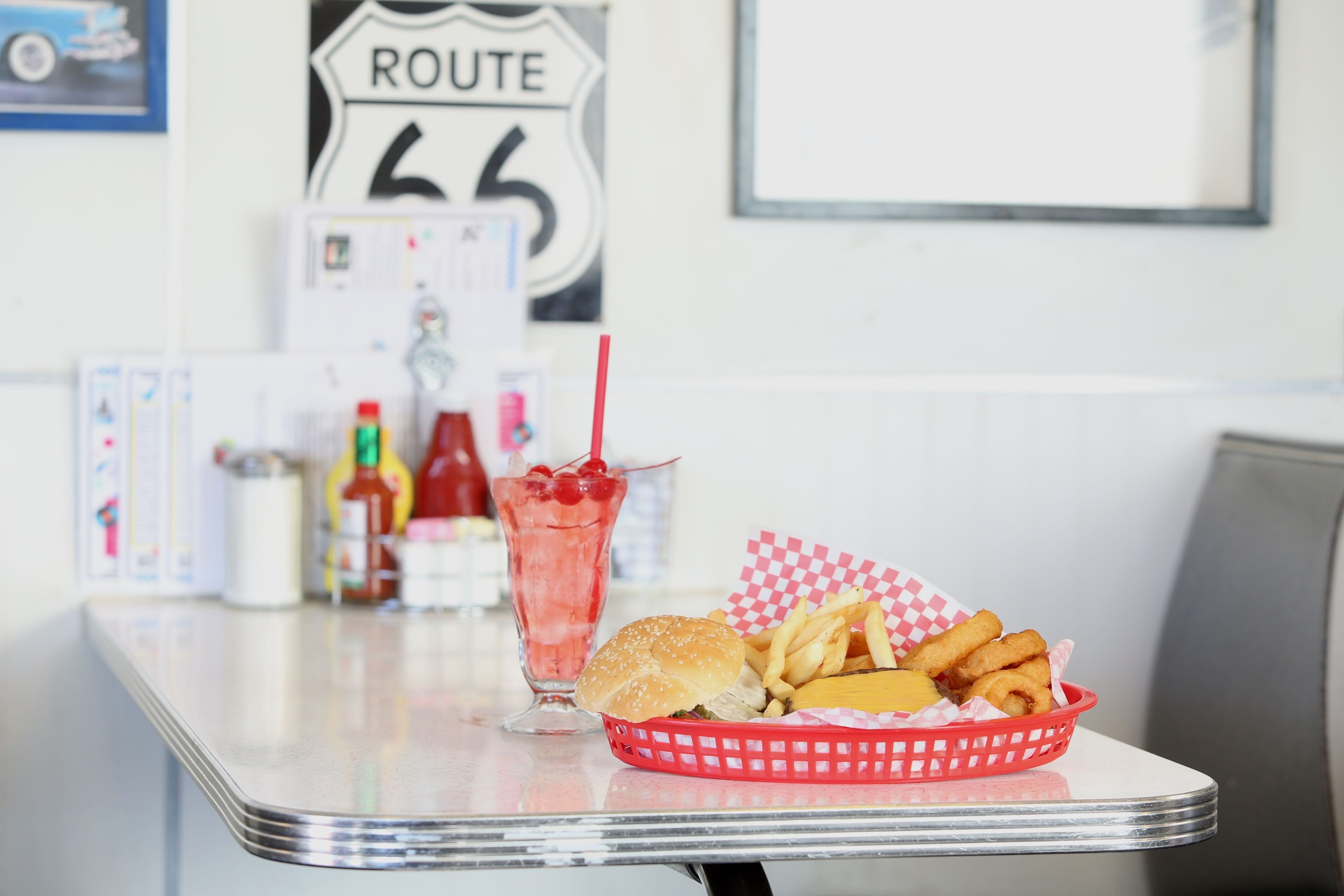 A table with a burger, fries, and a drink in a red basket.