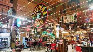 Un restaurante con letreros de neón, sillas rojas y un ambiente clásico.