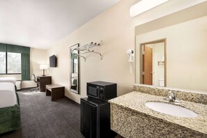 Une chambre d’hôtel équipée d’un lit, d’un bureau, d’un four à micro-ondes, d’un lavabo, d’un miroir, d’un sèche-cheveux et d’une télévision.