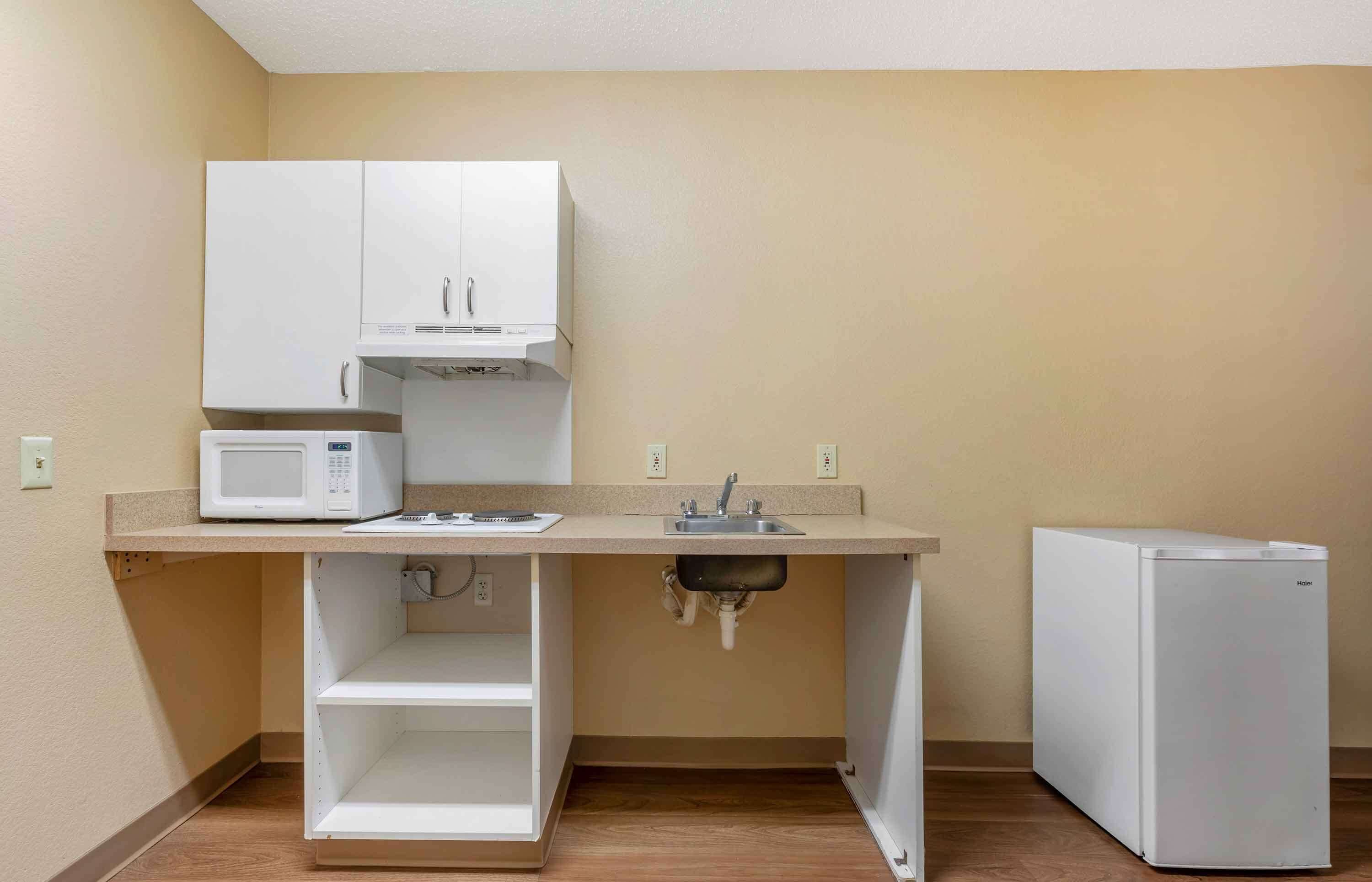 A compact kitchenette with a microwave, sink, and refrigerator.