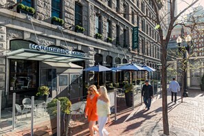 A building with a sign reading "Harborside Lounge" and outdoor seating with umbrellas.