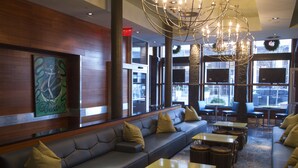 A modern lobby with leather seating, tables, and a large chandelier.