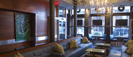 A modern lobby with leather seating, tables, and a large chandelier.