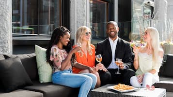 Eine Gruppe von Personen sitzt auf einem Sofa, vor ihnen steht ein Tisch mit Getränken und einem Teller Essen.