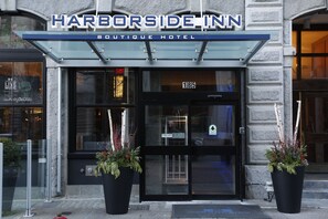 The exterior of the Harborside Inn Boutique Hotel with a glass entrance, numbered room 185, and two large potted plants at the entrance. - Harborside Inn Of Boston (Boston)