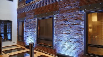 A modern interior with exposed brick walls, large windows, and a glass railing.