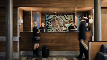 Una recepción con un diseño de panel de madera, un mural grande y una lámpara moderna.