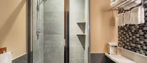 A modern bathroom with a glass-enclosed shower, a white sink, and a tiled backsplash.