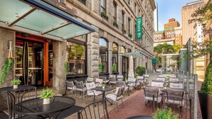 An outdoor cafe with tables and chairs, a building entrance, and a street sign.