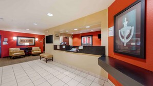 A reception area with a 'WELCOME' sign, a reception desk, two leather sofas, a small table, and a framed artwork on the wall. - Extended Stay America Suites Orange County Huntington Beach (Huntington Beach)