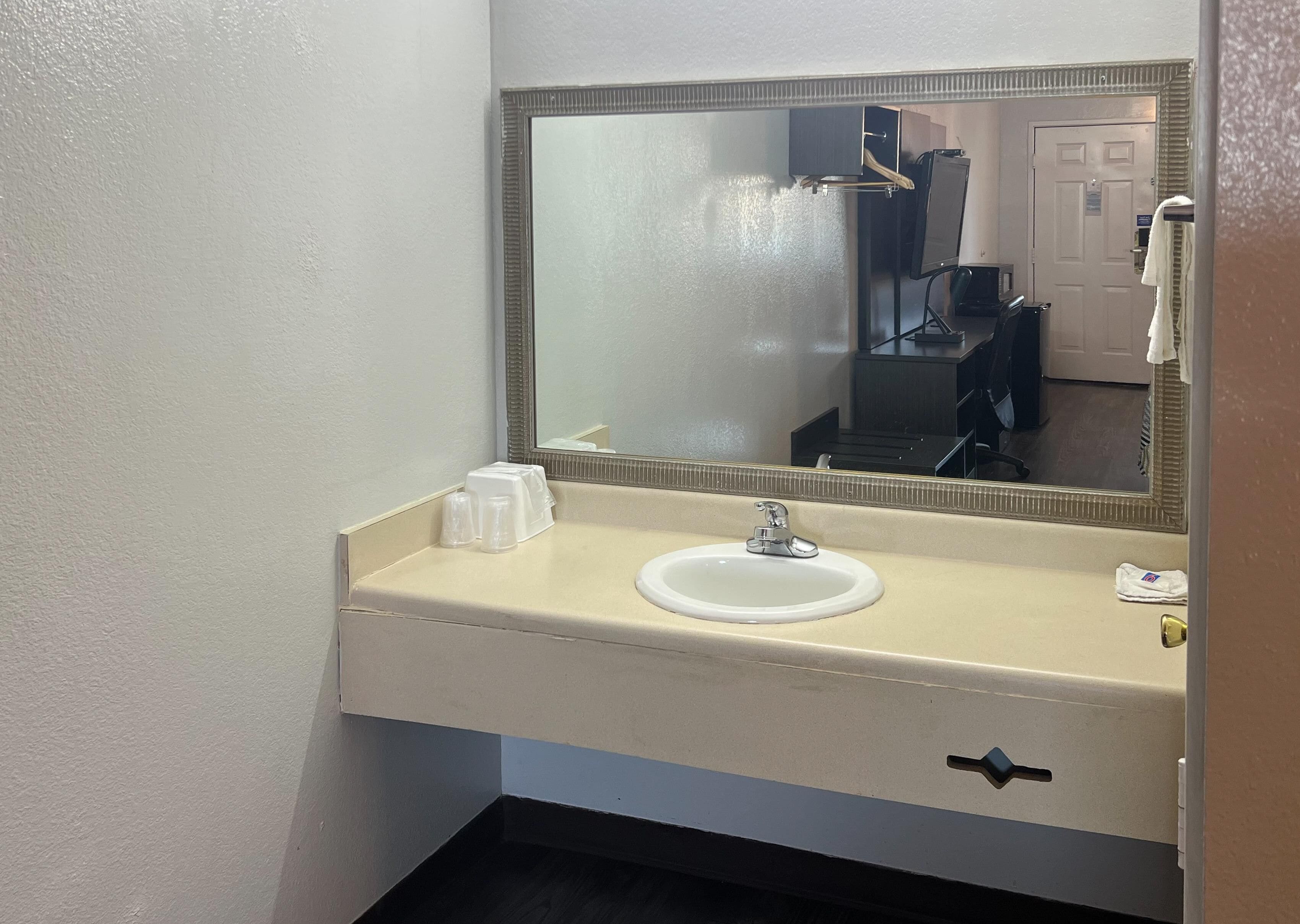 Une salle de bain avec un lavabo blanc, un miroir et un porte-serviettes.