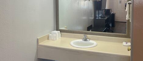 A bathroom with a white sink, a mirror, and a towel rack.