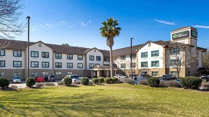 A hotel with multiple buildings, a parking lot, and a palm tree.