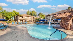 A swimming pool with blue lounge chairs and a water feature.