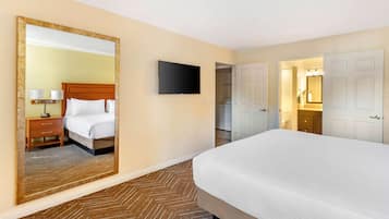 Una habitación de hotel con una cama grande, un televisor de pantalla plana, un espejo y un armario.