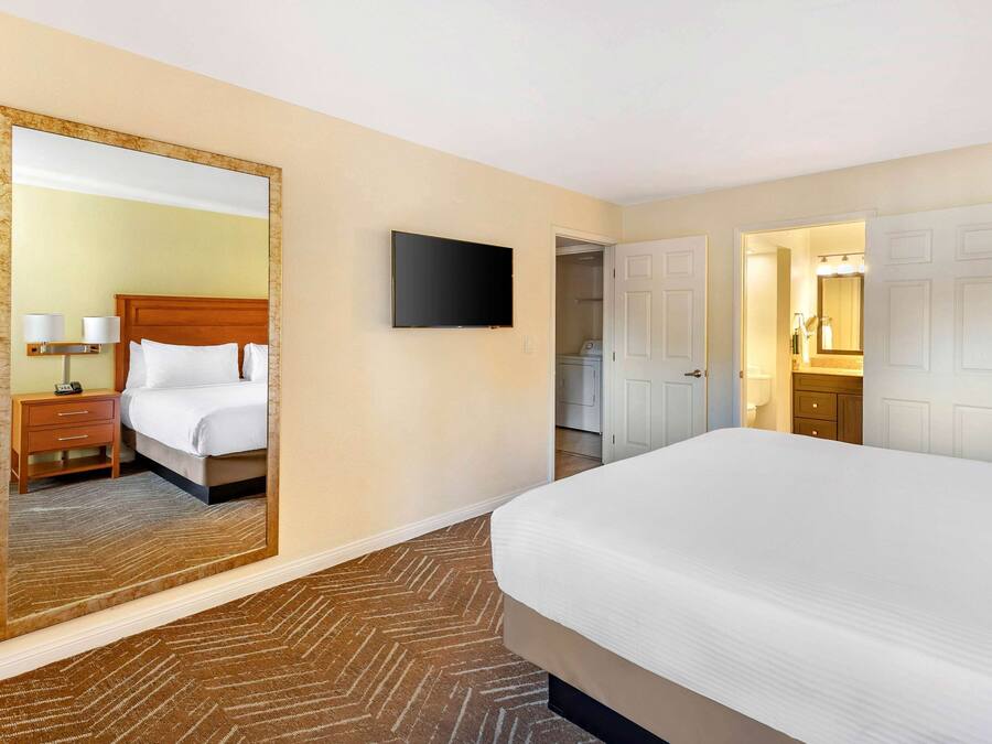 Une chambre d’hôtel avec un grand lit, un téléviseur à écran plat, un miroir et une armoire.