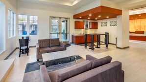 A spacious living area with a sofa set, a dining table, and a kitchen area with cabinets and a countertop.