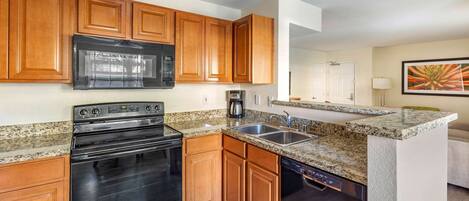 A kitchen with wooden cabinets, a black stove, a microwave, a coffee maker, and a dishwasher.