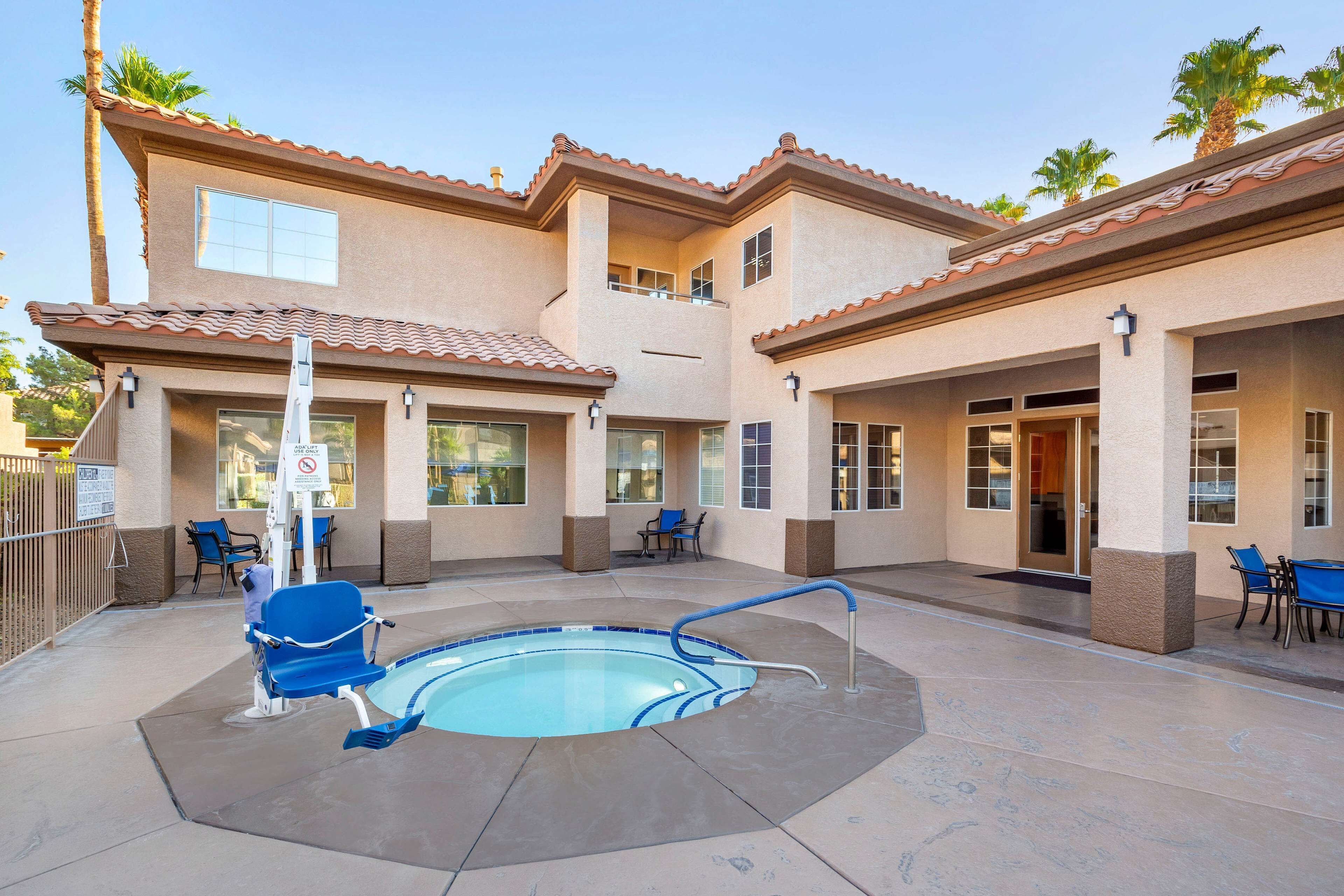 A pool area with a hot tub, lounge chairs, and a covered patio.