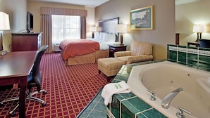 A hotel room with a bed, a desk, a chair, a sofa, a bathtub, and a television. - Country Inn & Suites by Radisson, Columbia, SC (Columbia)