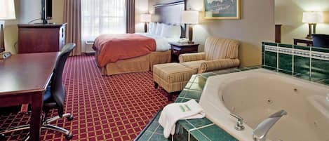 A hotel room with a bed, a desk, a chair, a sofa, a bathtub, and a television.