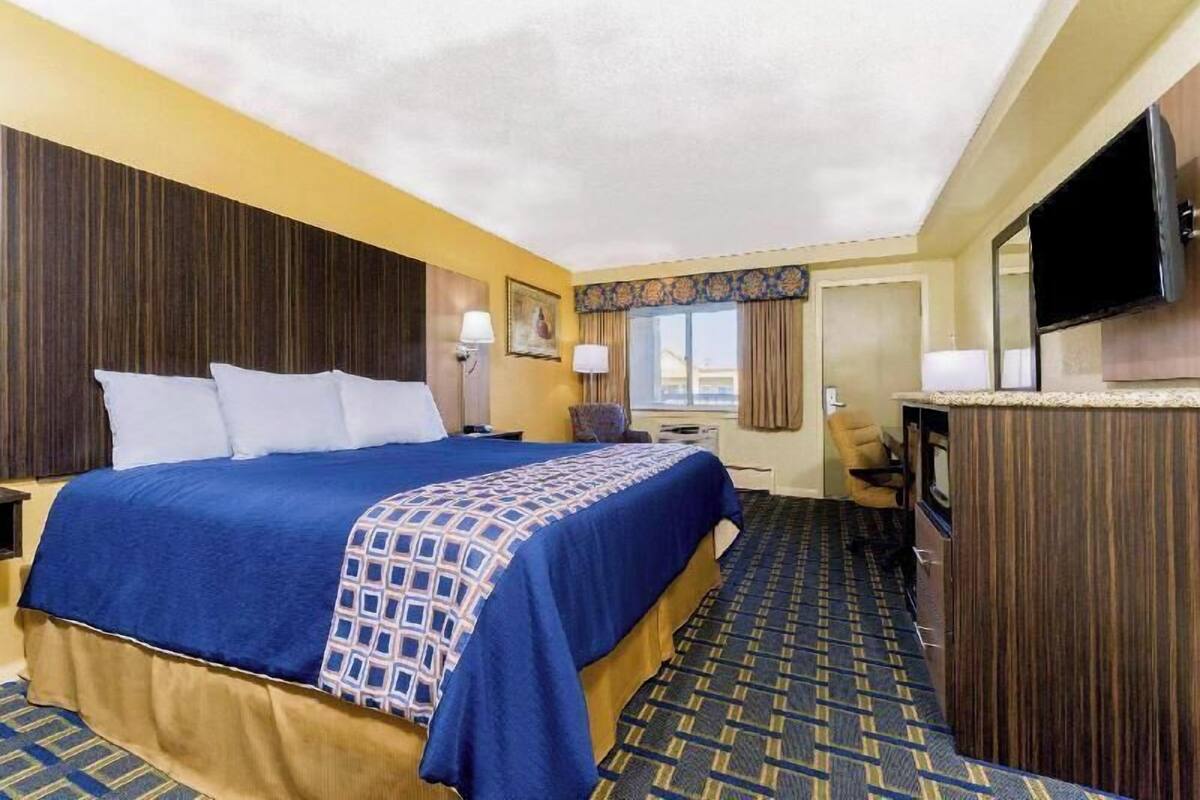 Une chambre d’hôtel avec un grand lit, un bureau, une télévision et une fenêtre avec des rideaux.