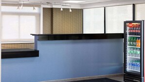 A hotel reception area with a counter, a vending machine, and a logo on the floor. - Days Inn by Wyndham Tonawanda/Buffalo (Tonawanda)