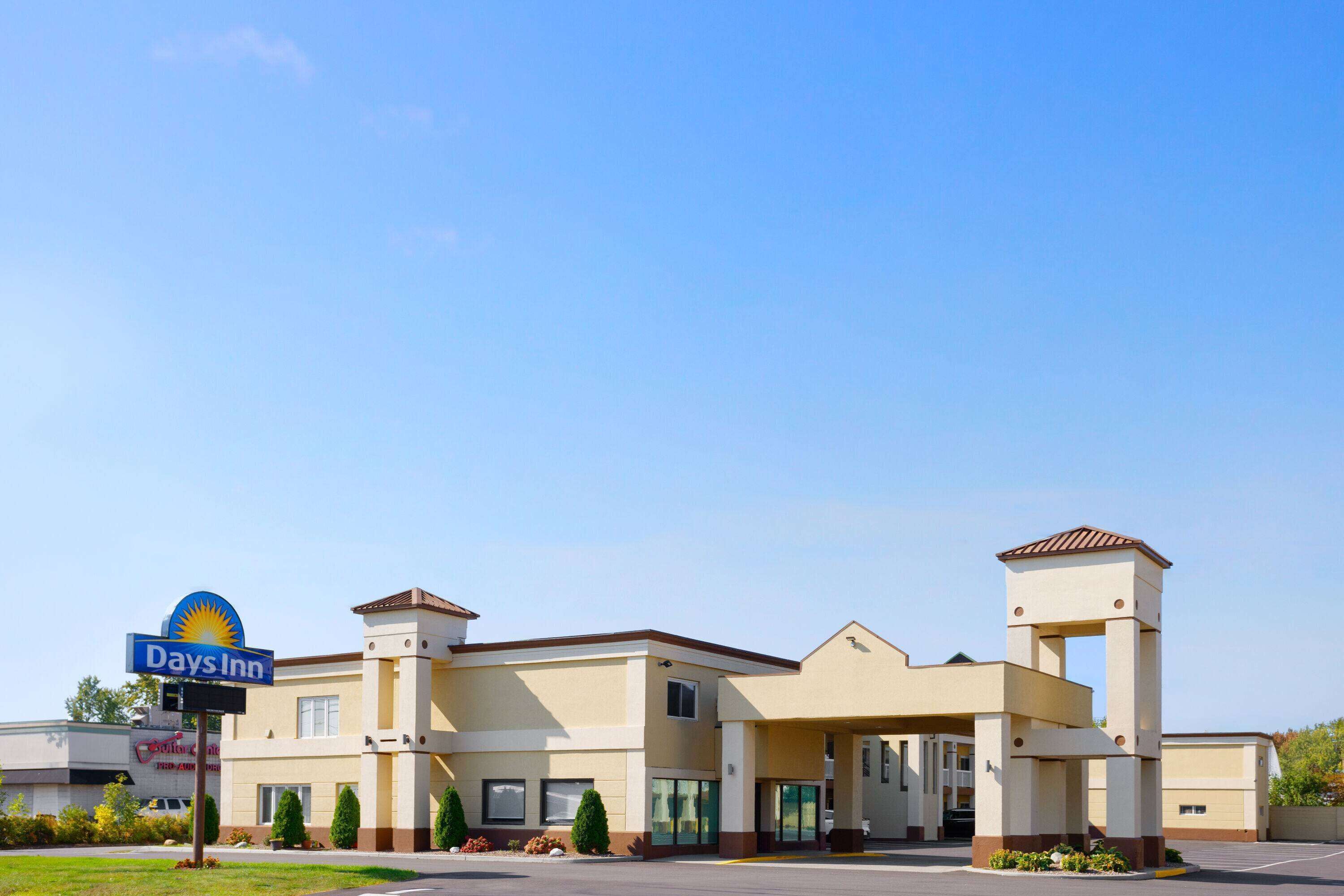 A Days Inn hotel with a modern design, featuring a central entrance, a covered patio area, and a parking lot.