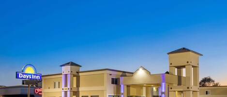 Ein Days Inn Hotel mit modernem Design, das einen zentralen Eingang, zahlreiche Fenster und einen Parkplatz bietet.