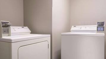 A laundry room with two white washing machines and a dryer.
