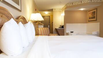 A hotel room with a large bed, a bedside table, a chair, a desk, a mirror, and a bathroom with a bathtub and sink.