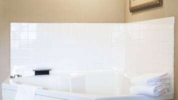 A bathroom with a white bathtub, a towel rack, and a framed picture on the wall.