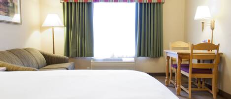 Quarto de hotel com uma cama grande, uma escrivaninha com cadeira, uma janela com cortinas e duas luminárias.