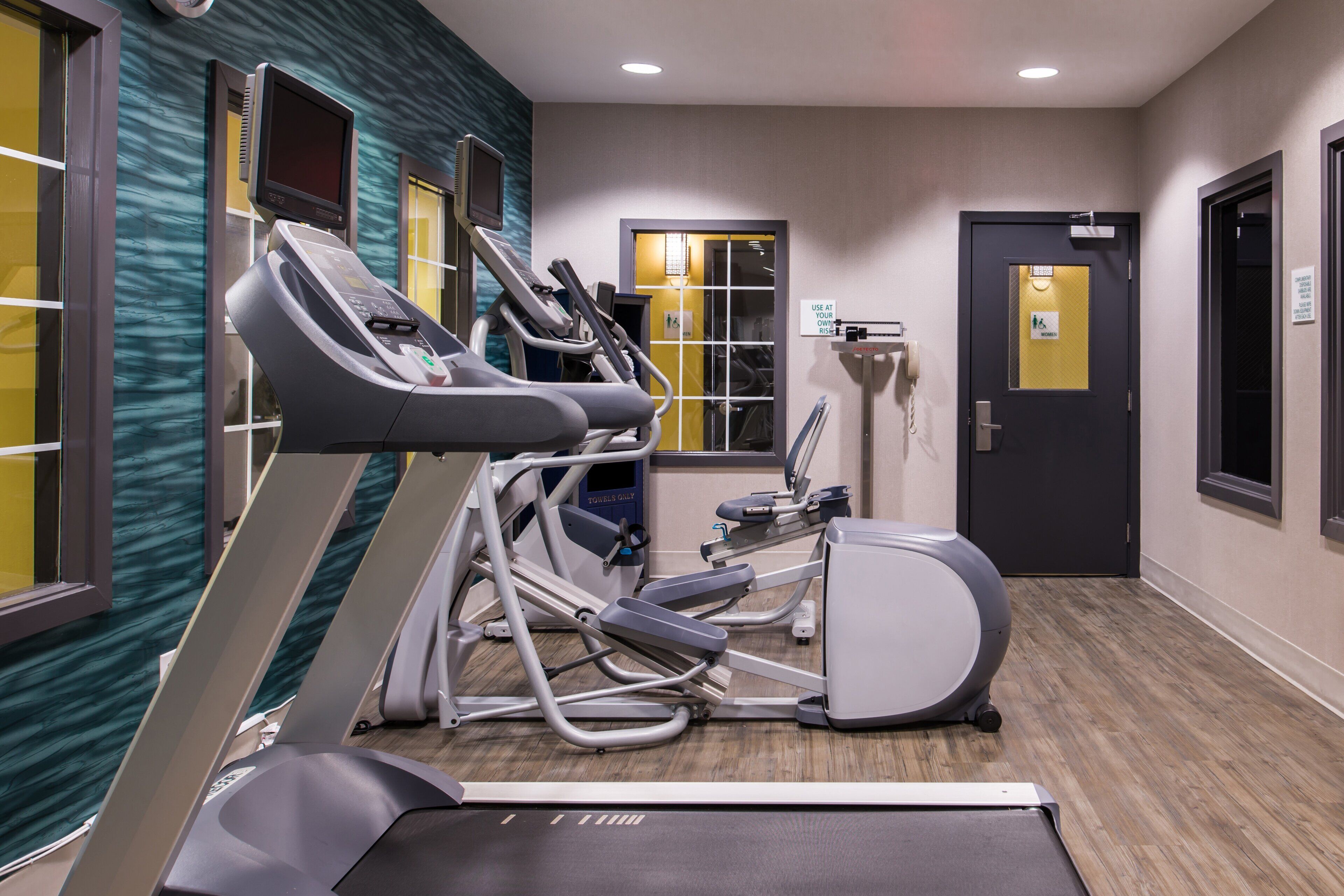 Une salle de remise en forme équipée de tapis de course, d’un vélo elliptique et d’un vélo d’appartement.