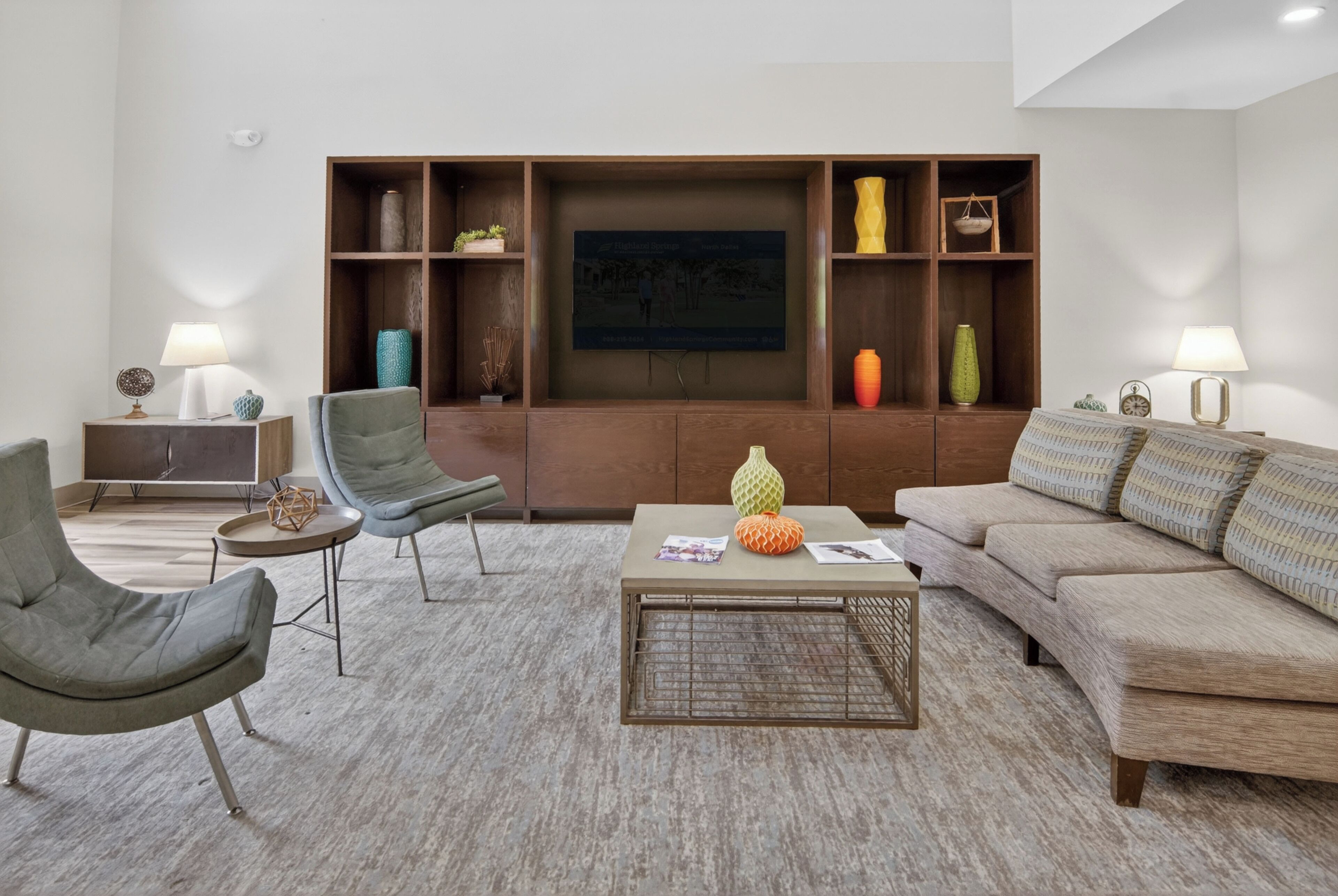 Un salon moderne comprenant un canapé, des fauteuils, une table basse et un meuble TV mural avec des étagères.