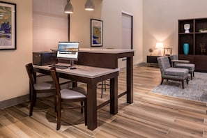 Et hotellets reception med skrivebord, stole, en computer og billeder i rammer på væggene.