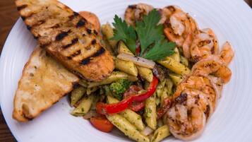 A plate of food with grilled shrimp, grilled bread, and a pasta dish with vegetables.