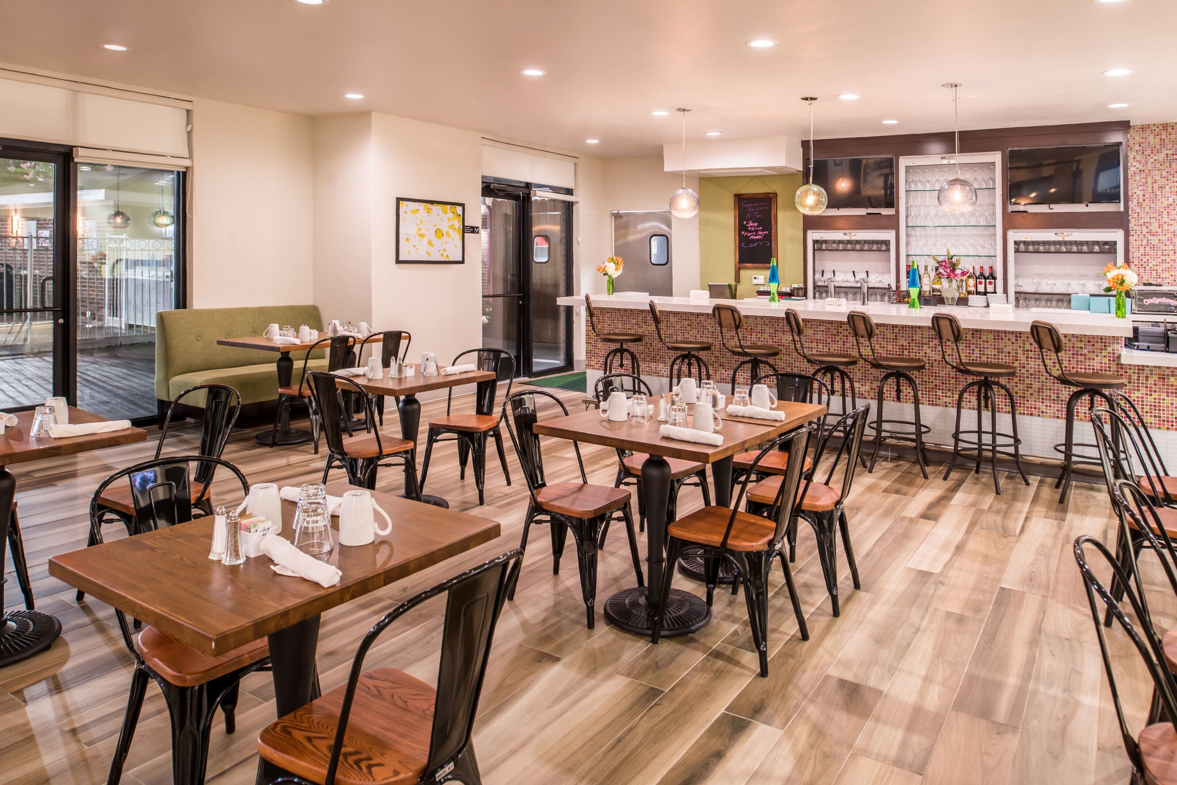 A restaurant with multiple tables and chairs, a bar area, and a refrigerator.