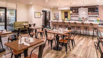 A restaurant with multiple tables and chairs, a bar area, and a refrigerator.
