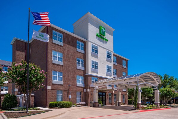 A Holiday Inn hotel with a brick facade, multiple windows, and a covered entrance area.